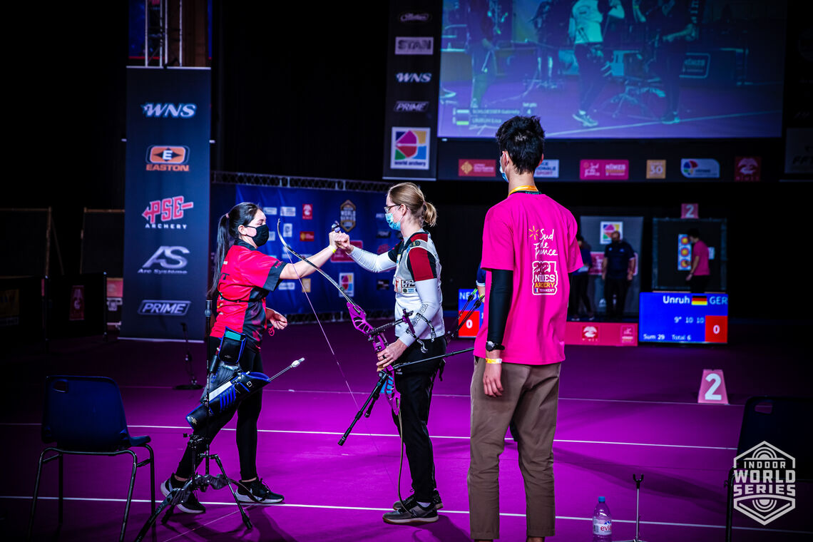 Gaby Schloesser and Lisa Unruh fist-bump during the finals at the Sud de France – Nimes Archery Tournament in 2021.