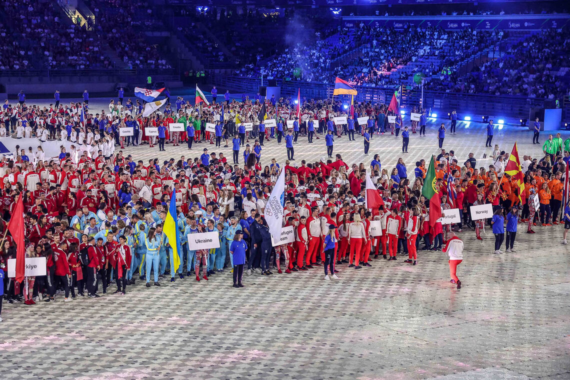 Flagbearers, including Anastasia Pavolva, stand at the front of national delegations.