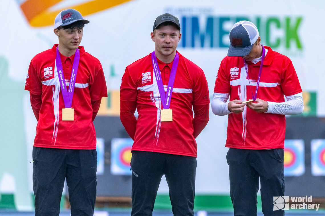 Mathias Fullerton inspects his medal on the podium after his Danish team wins the compound under-21 men’s team world title.