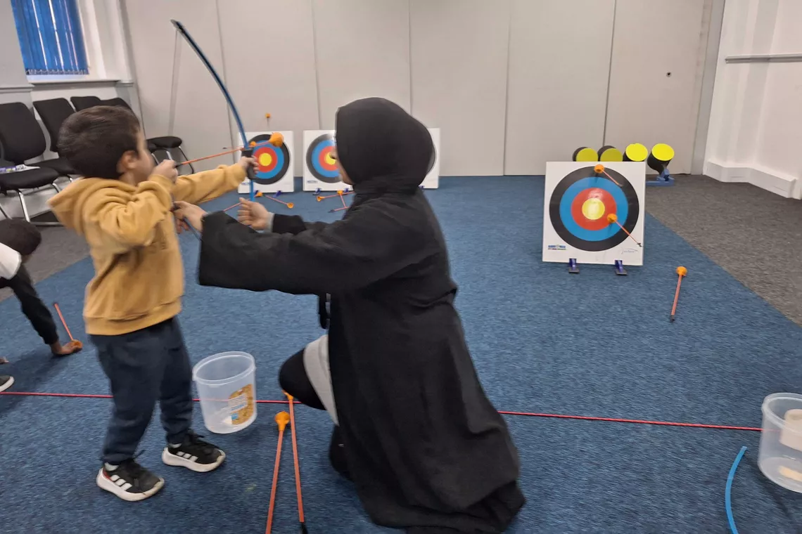 Jamila Bi teaching the archery form to a child