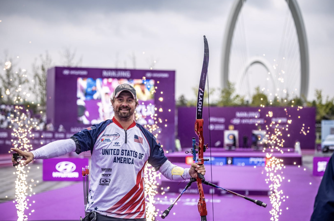 Brady Ellison celebrating with the Nanjing Eye Bridge in the background.