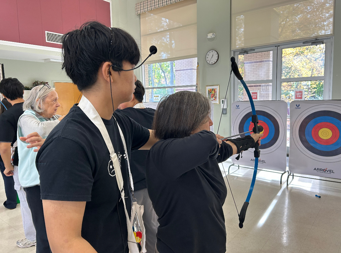 Samuel Kim watching over a senior at one of Aim for Unity's workshops.