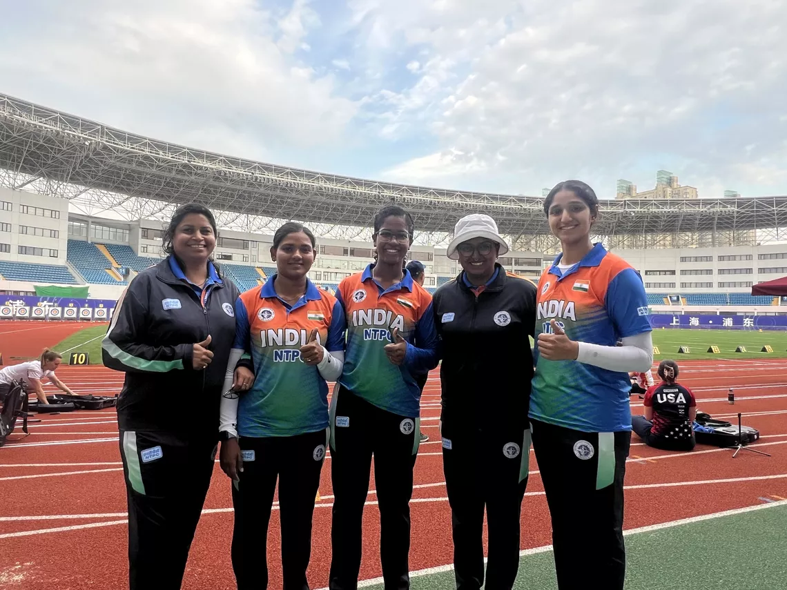 Athletes and coach strike a pose together