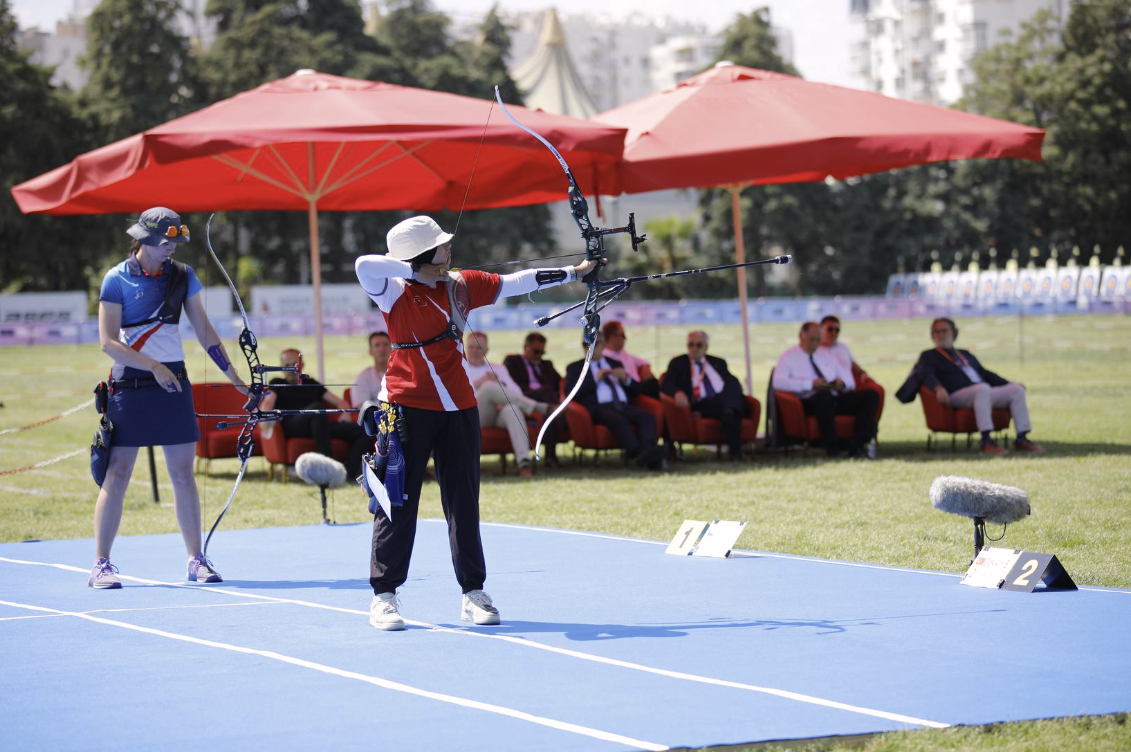 Elif Gokkir aiming with Marie Horackova waiting on the shooting line during their match.