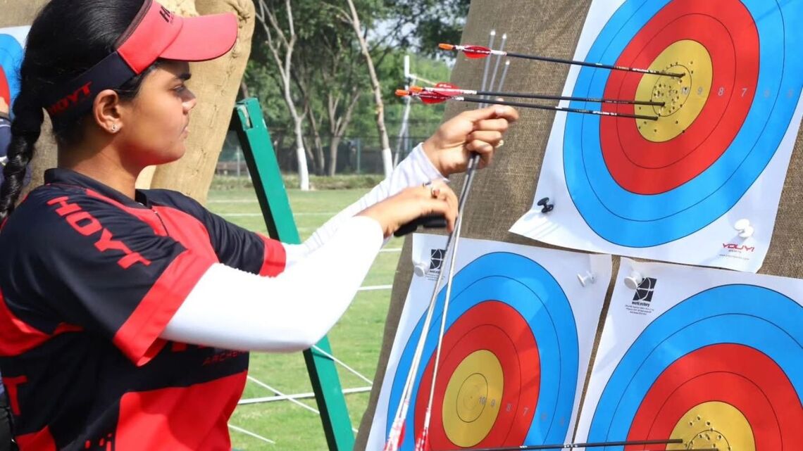 An archer checks her arrows at the target