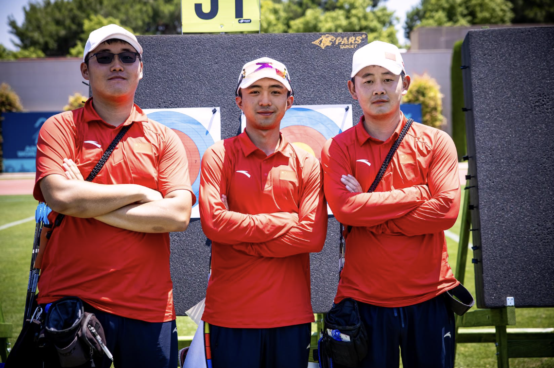 Jinyi, Jiahao and Jingyu posing for a photo with their arms crossed at the target at Antalya 2026.
