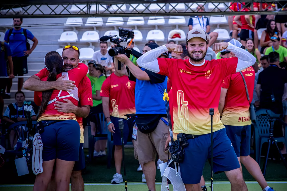 Andres Temino Mediel pumping his biceps after winning the recurve mixed team semifinal whilst Elia Canales hugs her coach at Madrid 2026.