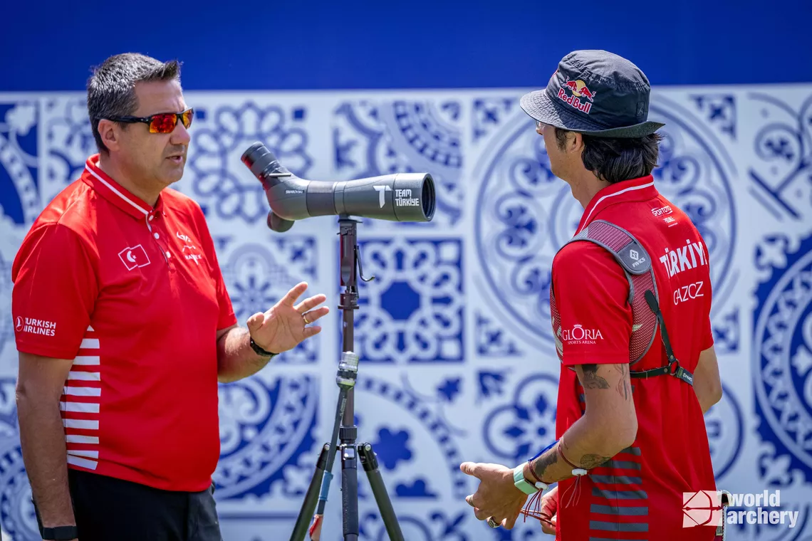 An archer speaks to his coach on the field