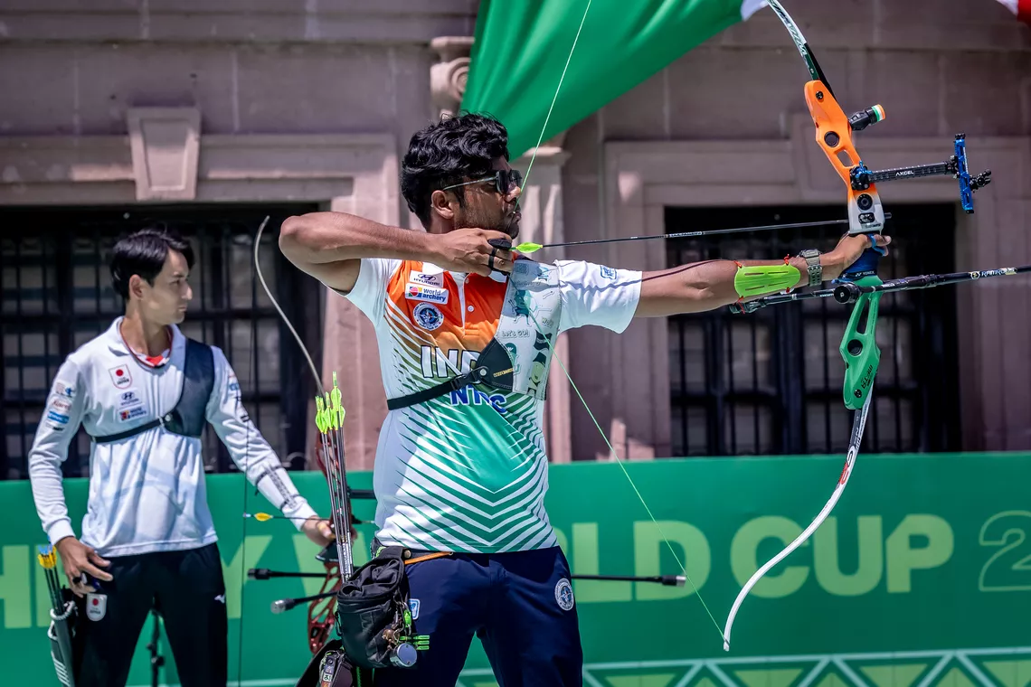 Dhiraj Bommadevara aiming with Junya Nakanish in the background at Saltillo 2026.