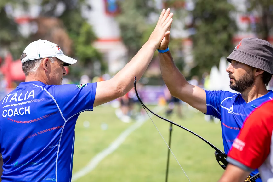 Mauro Nespoli high-fiving his coach Michele Frangilli. 