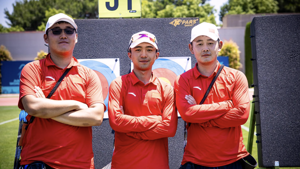 Jinyi, Jiahao and Jingyu posing for a photo with their arms crossed at the target at Antalya 2026.