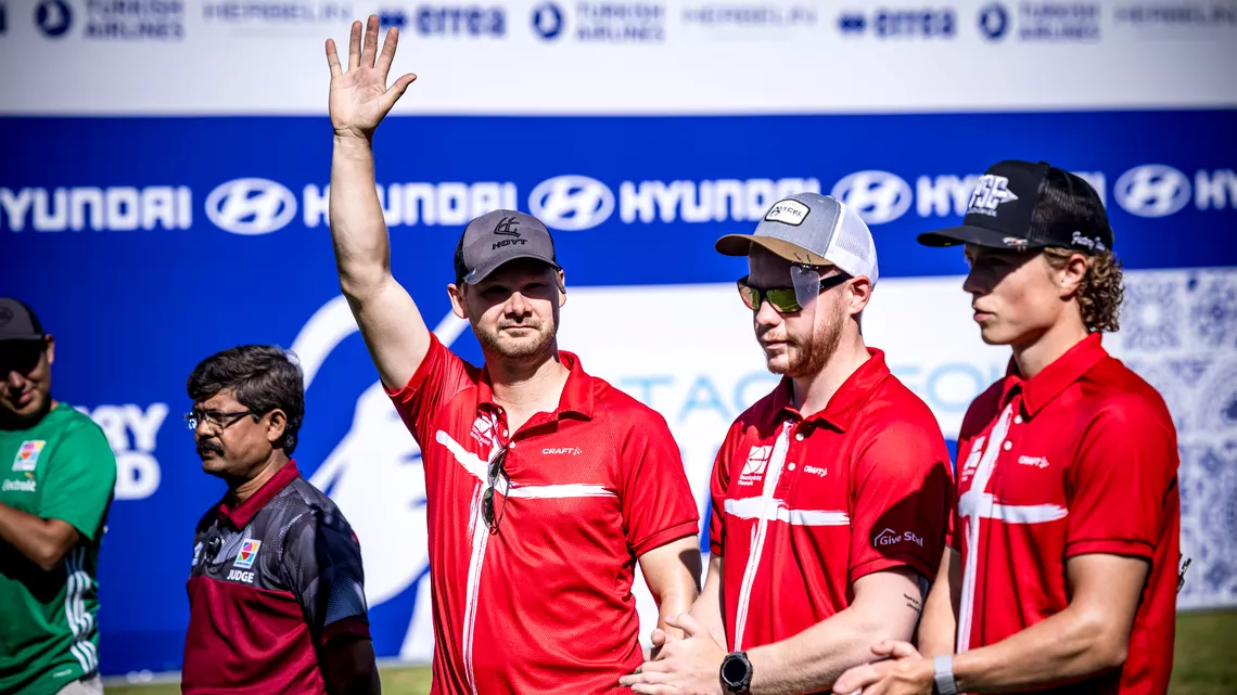 Martin Damsbo waving his hand in the air next to Ramsus Bramsen and Mathias Fullerton at Madrid 2026.