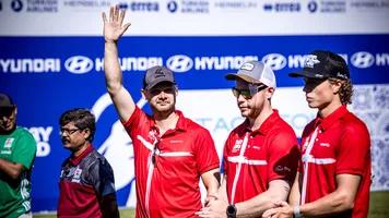 Martin Damsbo waving his hand in the air next to Ramsus Bramsen and Mathias Fullerton at Madrid 2026.